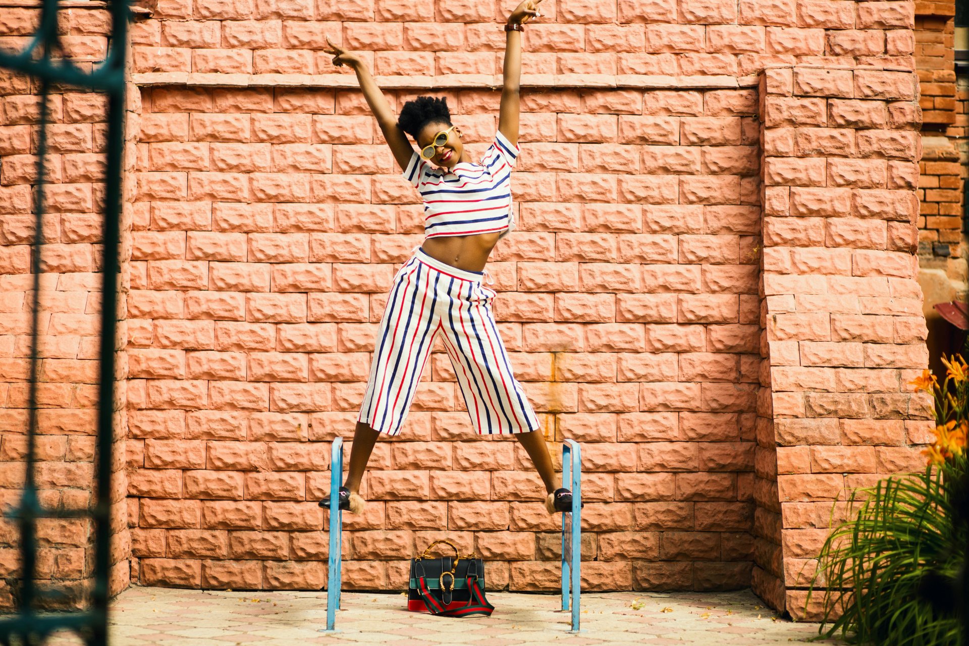 woman-striped-outfit-sunglasses-pink-brick-wall-1753227166240